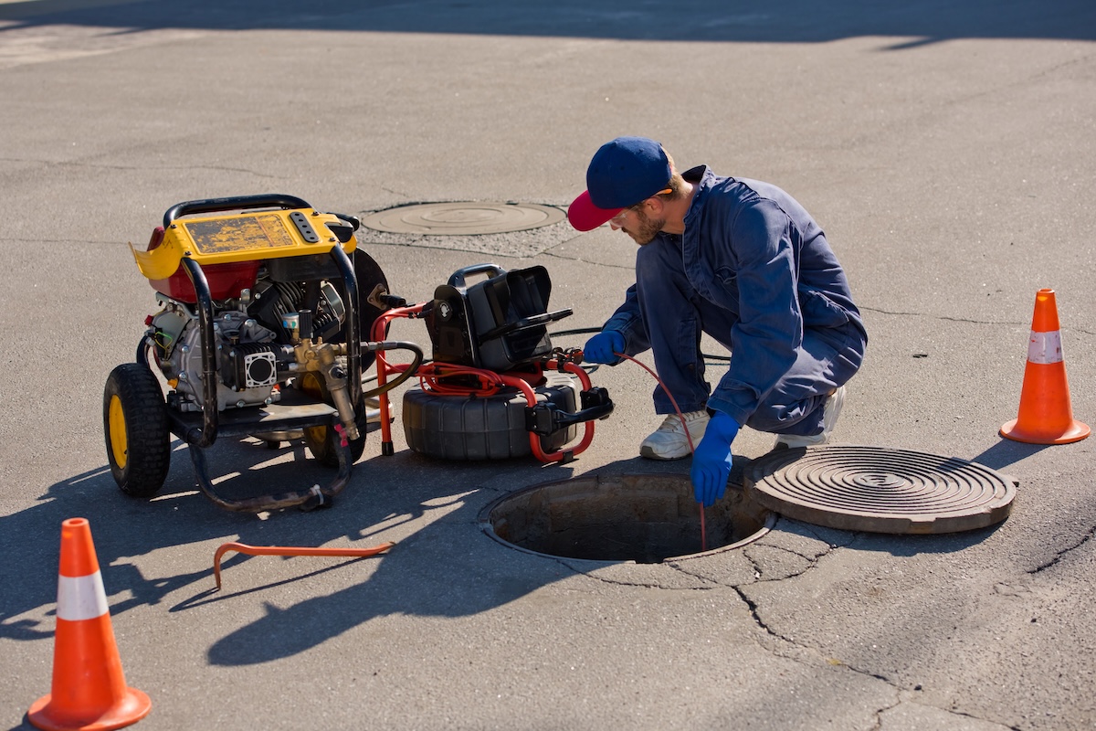 plumber diagnoses a drain well on the street using special equipment.