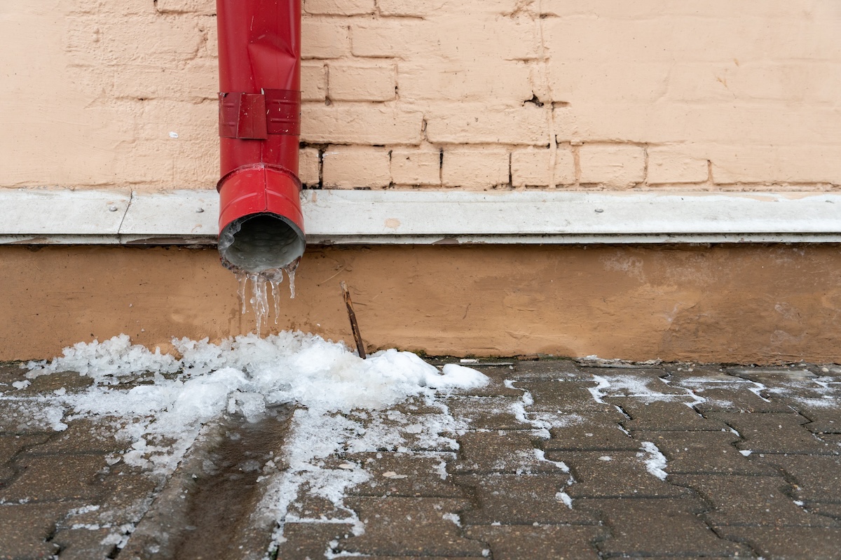 the drainpipes are covered with ice and snow. after a heavy snowstorm, the city is covered with snow and ice. there are many icicles on the facade of the building. ice on sidewalks and roads.